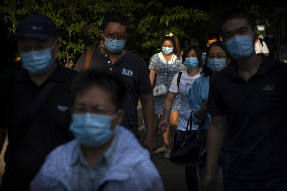 People wearing face masks to protect against the coronavirus walk along a street in the central business district in Beijing, Wednesday, Sept. 2, 2020. Even as China has largely controlled the outbreak, the coronavirus is still surging across parts of the world. (AP Photo/Mark Schiefelbein)