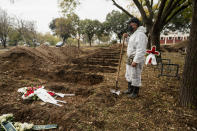 A worker stands over graves during a funeral ceremony for a person who died of COVID-19, in the northern city of Thessaloniki, Greece, Saturday, Dec. 5, 2020. Greece is on lockdown until Dec. 7 but government officials say it is too early to say when schools and businesses will reopen due to continued pressure on the state-run health service, with intensive care wards near capacity in parts of the country. (AP Photo/Giannis Papanikos)