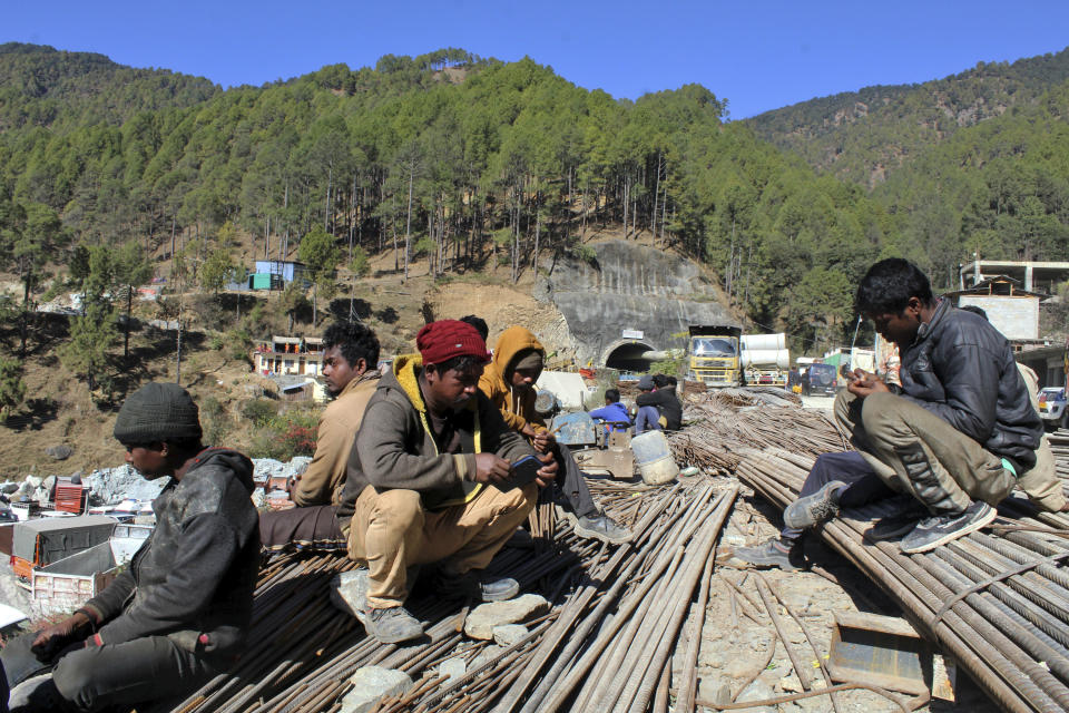 People wait by the site of an under-construction road tunnel that collapsed trapping 41 workers in Silkyara in the northern Indian state of Uttarakhand, Wednesday, Nov. 22, 2023. The workers have been trapped for over a week, as rescuers work on an alternate plan of digging toward them vertically. (AP Photo)