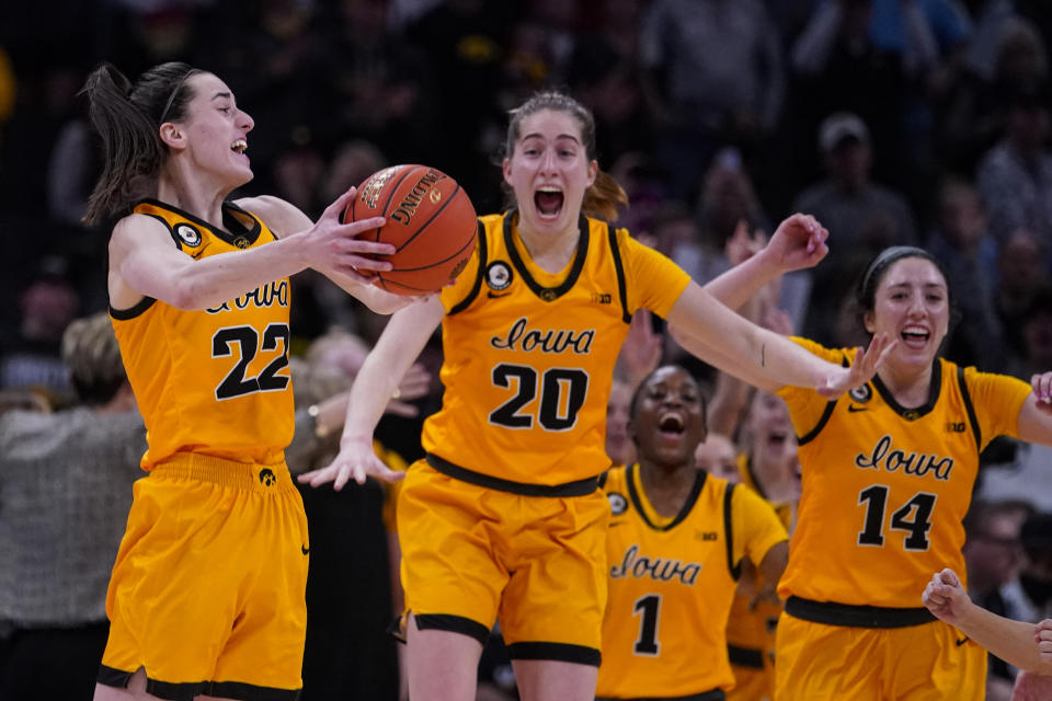 Iowa's Caitlin Clark (22), Kate Martin (20) and McKenna Warnock (14) celebrate as they win an NCAA college basketball game against Indiana for the championship of the Big Ten Conference tournament in Indianapolis, Sunday, March 6, 2022. Iowa defeated Indiana 74-67. (AP Photo/Michael Conroy)