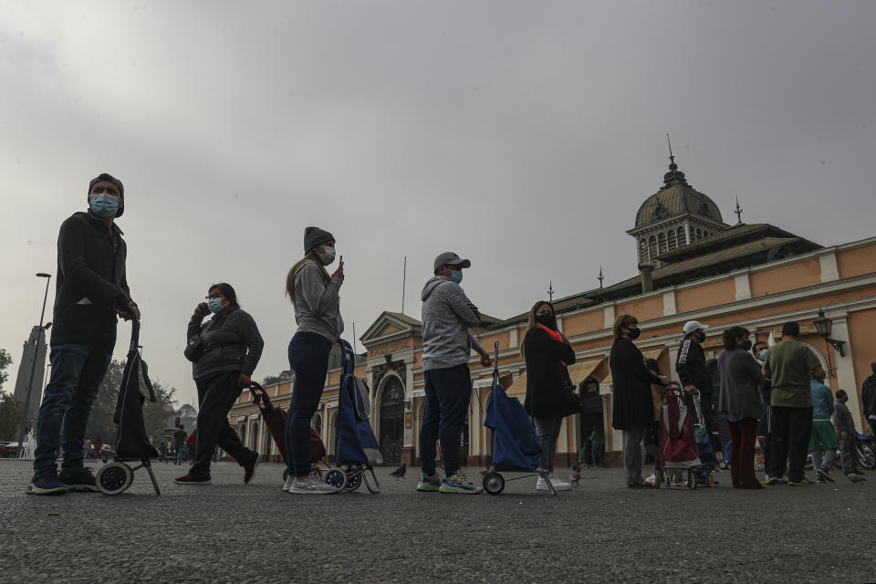 Varias personas permanecen en fila para comprar pescado para la Semana Santa en el mercado central en medio de la pandemia del coronavirus en Santiago de Chile, el jueves 1 de abril de 2021. La ciudad reimpuso restricciones a la movilidad para intentar contener un repunte de casos de COVID-19. (AP Foto/Esteban Félix)