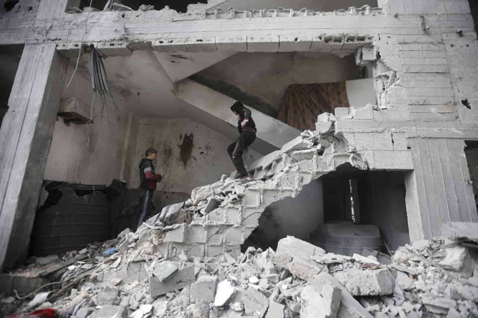 Palestinian kids walk inside a destroyed apartment building after an Israeli strike in Kahan Younis, Gaza Strip, Friday, Jan. 12, 2024. AP Photo/Mohammed Dahman)