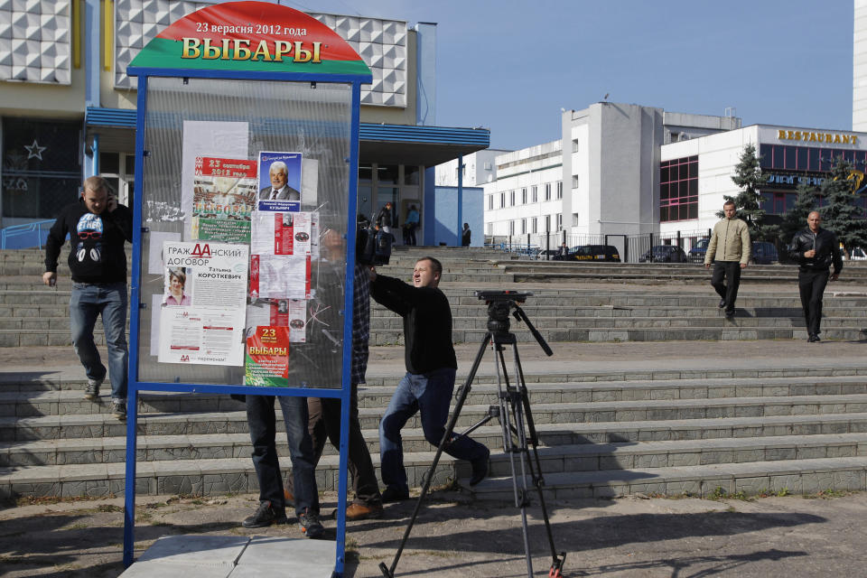 Belarus plainclothes security officer centre right, reaches his hand to grab a journalist's camera as two another run, right, in Minsk , Tuesday, Sept. 18, 2012. Associated Press photographer Sergei Grtts was beaten and briefly detained by plainclothes security officers in the Belarusian capital. Sergei Grits says he was among eight journalists covering a protest by four opposition activists calling for a boycott of this weekend's parliamentary elections when plainclothes security officers attacked them in downtown Minsk. (AP Photo/Sergei Grits)