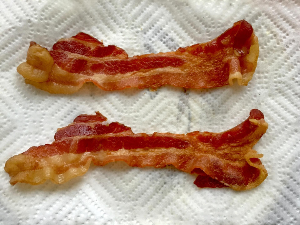 Cooked bacon cooling on paper towels.