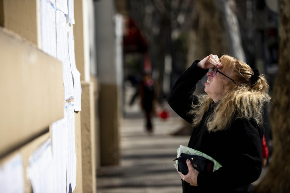 A woman looks for her polling station number outside a school during primary elections in Buenos Aires, Argentina, Sunday, Aug. 11, 2019. Argentina is holding primary elections Sunday which are expected to provide a hint of who might win ahead of October's presidential elections. (AP Photo/Tomas F. Cuesta)