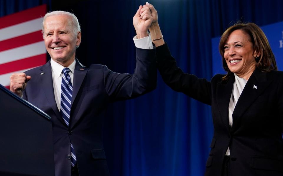 President Joe Biden, left, and Vice President Kamala Harris stand on stage at the Democratic National Committee winter meeting