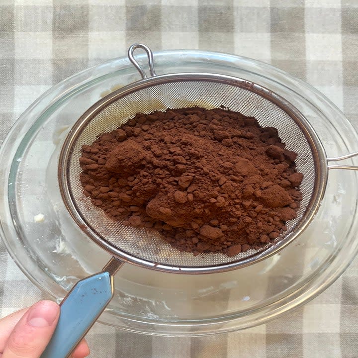 cocoa powder being sifted into a bowl