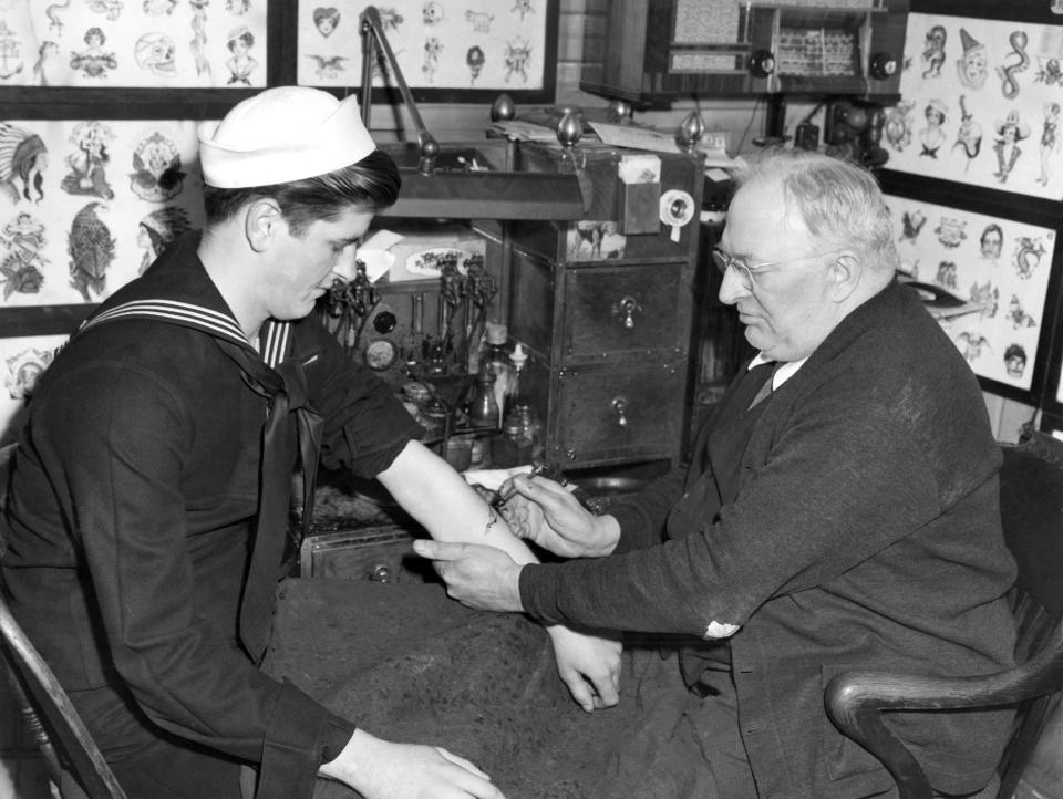 Edward "Dad" Liberty works in his shop in Boston on May 12, 1942, on sailor Roy Nordstrom of Walpole, Mass. War has churned an upsurge in the tattooing business in Boston's Scollay Square, known throughout the world as a mecca for soldiers and sailors at play.
