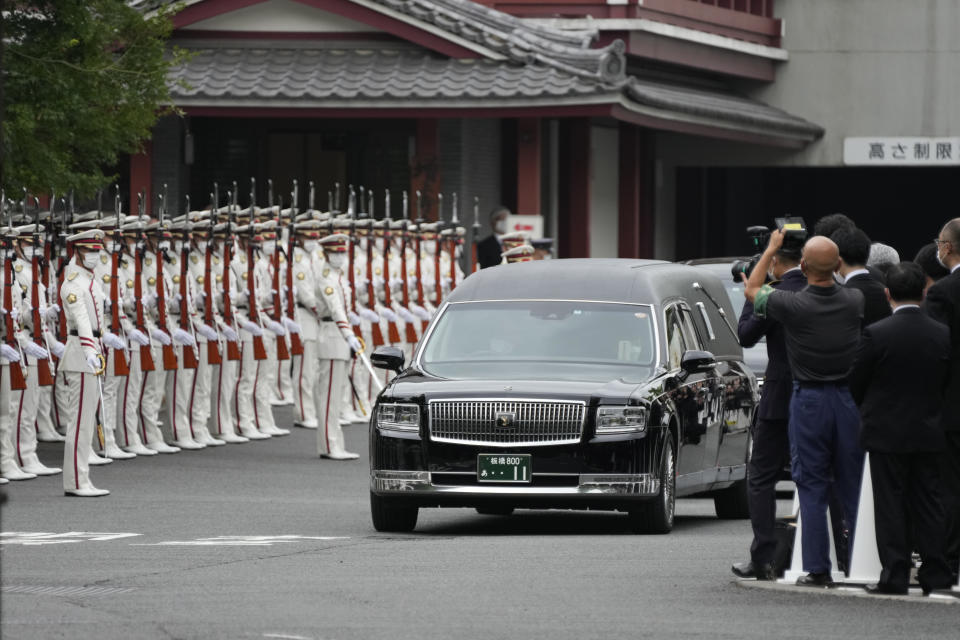 The hearse carrying the body of former Japanese Prime Minister Shinzo Abe moves through between an honor guard and attendants as it leaves Zojoji temple after his funeral in Tokyo on Tuesday, July 12, 2022. Abe was assassinated Friday while campaigning in Nara, western Japan. (AP Photo/Hiro Komae)