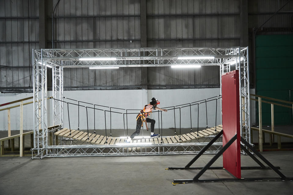 Contestant Daniel walking across a bridge with a VR headset on.