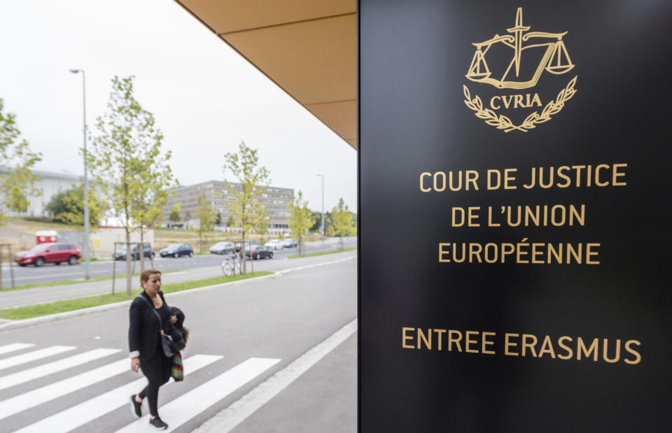 File - In this Oct. 5, 2015 file photo, a woman walks by the entrance to the European Court of Justice in Luxembourg. A European Union high court on Wednesday, July 15, 2020 ruled in favor of technology giant Apple and Ireland in its dispute with the EU over 13 billion euros, 15 billion US dollars in back taxes. (AP Photo/Geert Vanden Wijngaert, File)