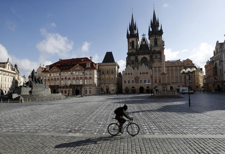 A man rides his bicycle walks at the Old Town Square in Prague, Czech Republic, Monday, March 22, 2021. A group of activists painted the crosses to criticize the government's response to the coronavirus pandemic. (AP Photo/Petr David Josek)