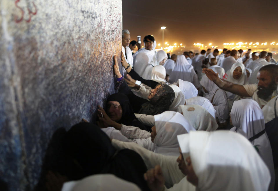 Muslim pilgrims pray in front of a pillar, where Islam's Prophet Muhammad is believed to have delivered his last sermon to tens of thousands of followers, on a rocky hill known as Mountain of Mercy, on the Plain of Arafat, during the annual hajj pilgrimage, ahead of sunrise near the holy city of Mecca, Saudi Arabia, Saturday, Aug. 10, 2019. More than 2 million pilgrims were gathered to perform initial rites of the hajj, an Islamic pilgrimage that takes the faithful along a path traversed by the Prophet Muhammad some 1,400 years ago. (AP Photo/Amr Nabil)