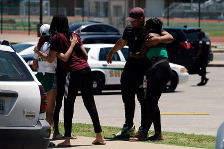 A group of young people hug each other in front of a high school the day after violent clashes between police and protesters in the streets at night in Memphis