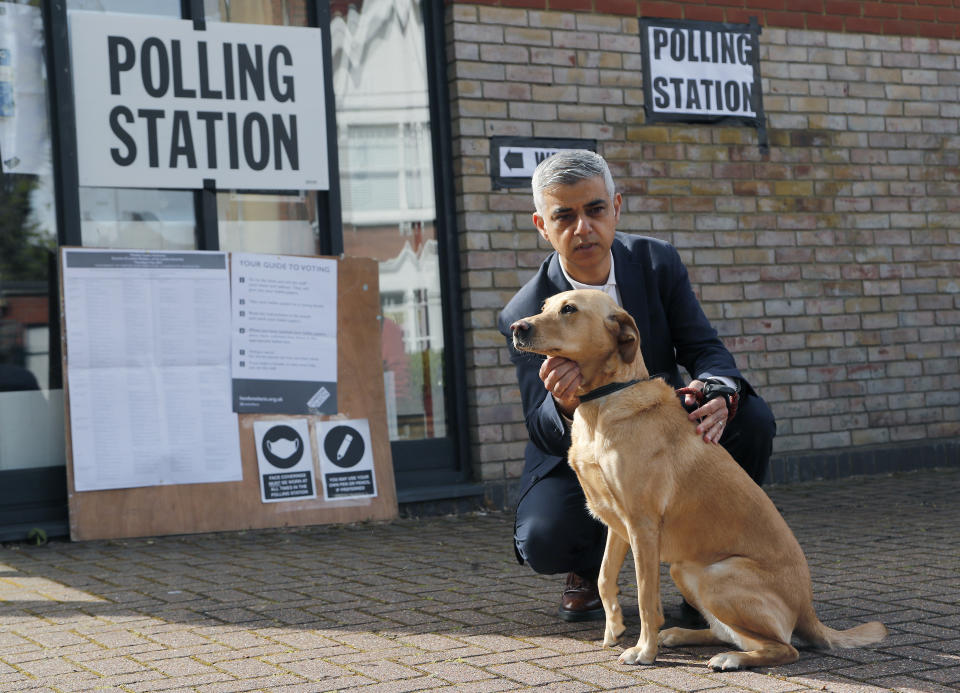 Mayor of London Sadiq Khan holds his dog Luna as his wife Saadiya votes at St Albans Church in London, Thursday, May 6, 2021. Khan voted by post. Millions of people across Britain will cast a ballot on Thursday, in local elections, the biggest set of votes since the 2019 general election. A Westminster special-election is also taking place in Hartlepool, England. (AP Photo/Frank Augstein)