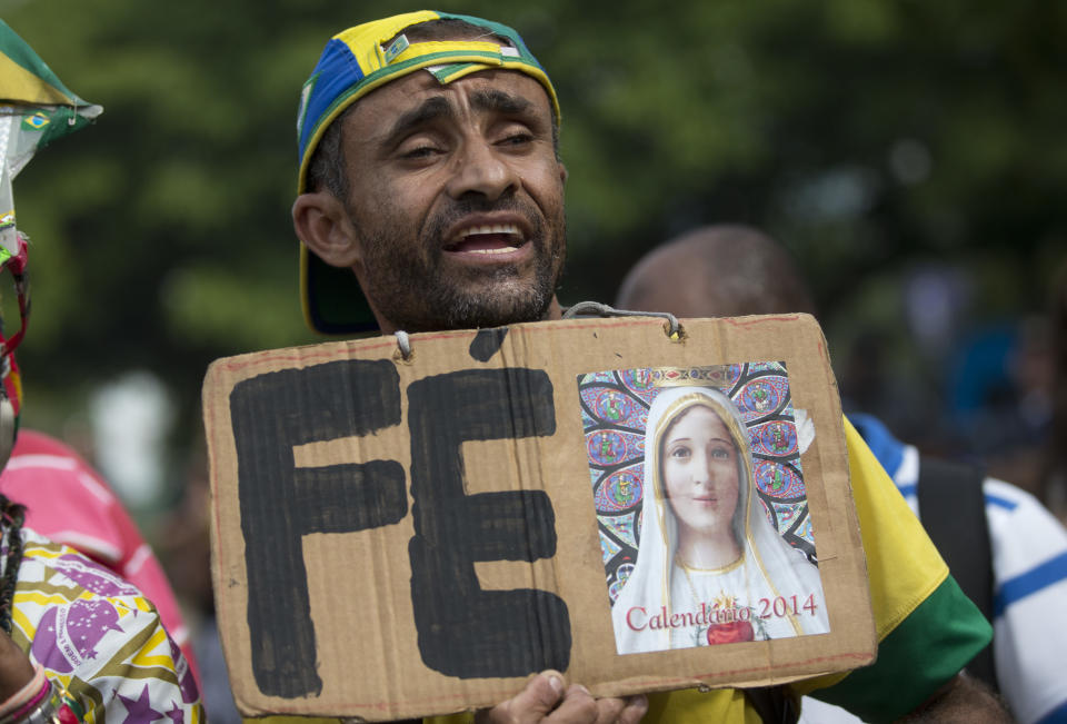 A Brazil soccer fan holds a sign that reads in Portuguese "Faith" outside the venue where coach Luiz Felipe Scolari announced his squad for the upcoming international soccer tournament in Rio de Janeiro, Brazil, Wednesday, May 7, 2014. The team will mix talented young stars such as Neymar and Oscar with more experienced players such as Dani Alves, David Luiz, Thiago Silva and Hulk. Past stars such as Ronaldinho, Kaka and Robinho were left off the squad as expected. (AP Photo/Silvia Izquierdo)