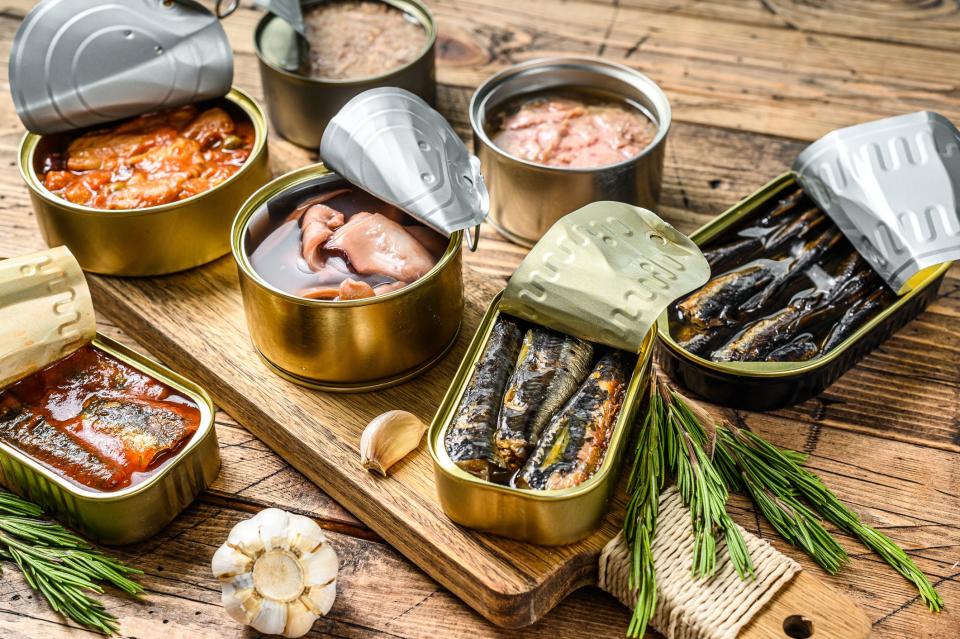 an array of open cans of tinned dish along with a few cloves of garlic and sprigs of rosemary.