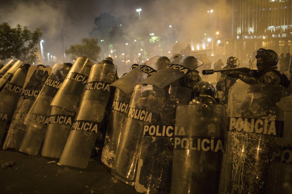 Police officers shield themselves from rocks thrown by protesters who were trying to march to Congress in a demonstration against the removal of President Martin Vizcarra, in Lima, Peru, Thursday, Nov. 12, 2020. On Tuesday, Manuel Merino was sworn in as the country's president, after the legislature voted Vizcarra out of office Monday. (AP Photo/Rodrigo Abd)