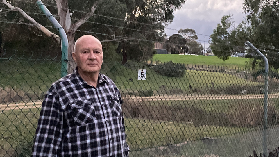 Ian Fairweather's stands in front of the fence at the edge of his backyard. 