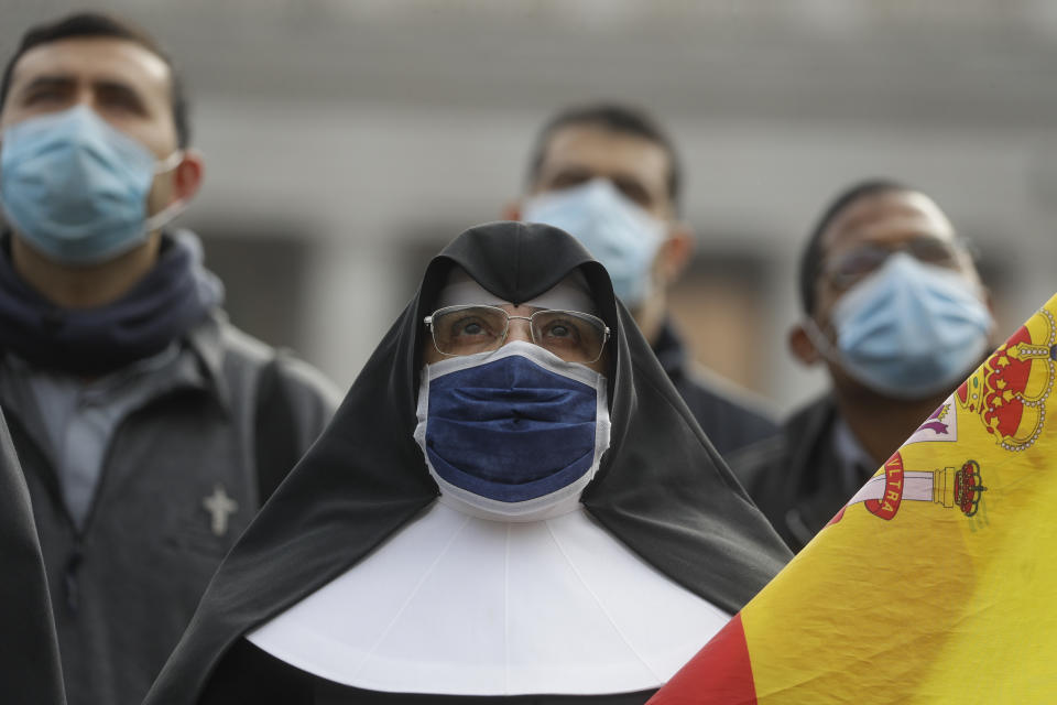 A nun wearing a face mask as she looks up at Pope Francis reciting the Angelus prayer from his studio window overlooking St.Peter's Square at the Vatican, Sunday, Nov. 29, 2020. Pope Francis, joined by the church's newest cardinals at Mass, has warned against mediocrity as well as promoting one's career rise. (AP Photo/Gregorio Borgia)