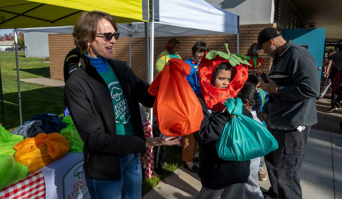 Amber Stott, left, founder of the Food Literacy Center, stands with volunteer Donovan Hall-Ramsey, 9, to hand out 50 food kits and recipes at John Sloat Elementary School earlier this month for kids to take home and cook. The Food Literacy Center Kitchen is asking Book of Dreams for $4,500 for supplies to help the program.