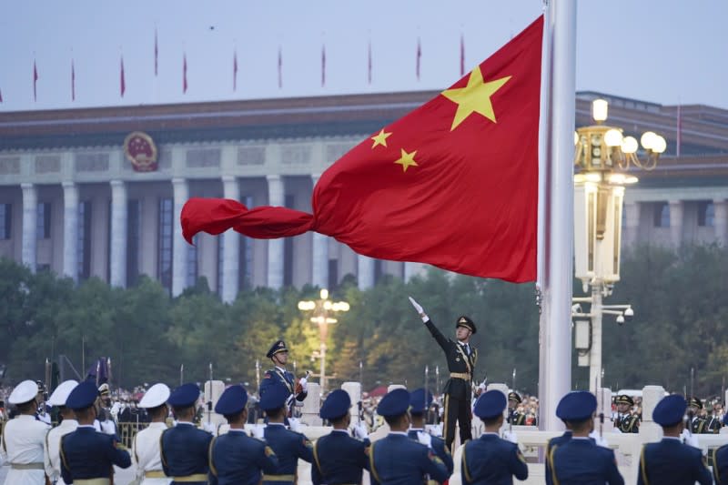<cite>一名解放軍的儀仗隊成員在天安門廣場的慶祝中華人民共和國成立73週年升旗儀式上展開中國國旗。（美聯社）</cite>