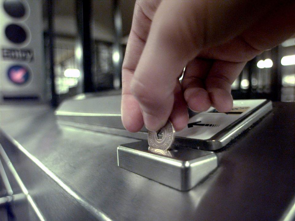 Close-up of subway token being dropped into slot at Penn Station.