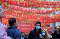 People wear masks as they walk in Chinatown district, in London