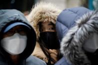 People wearing masks after the coronavirus outbreak wait in a line to buy masks in front of a department store in Seoul