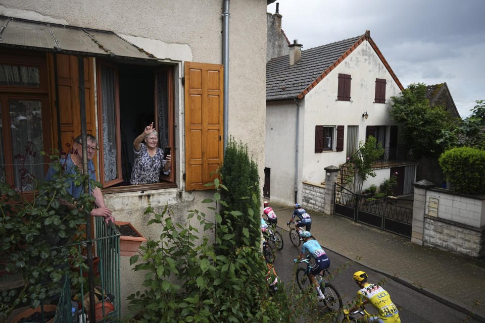 Residents watch the pack with Slovenia's Tadej Pogacar, wearing the overall leader's yellow jersey, pass through their village during the sixth stage of the Tour de France cycling race over 163.5 kilometers (101.6 miles) with start in Macon and finish in Dijon, France, Thursday, July 4, 2024. (AP Photo/Daniel Cole)