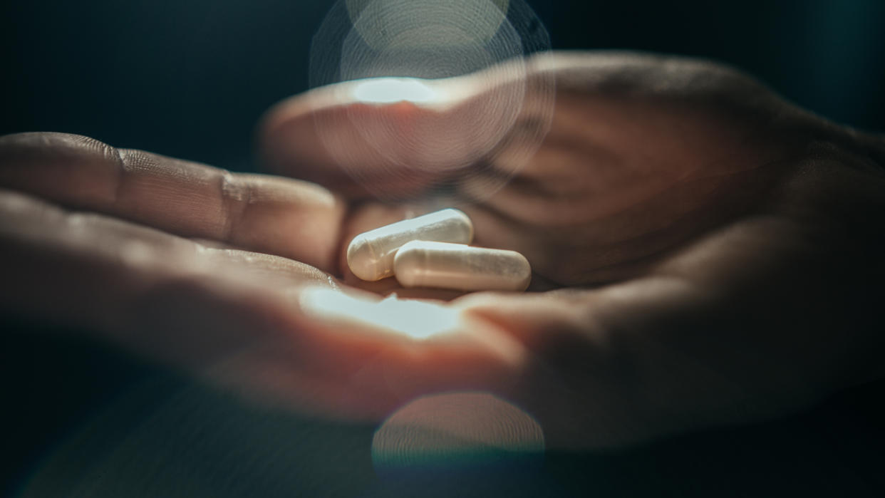 A person holding pills in the palm of their hand.