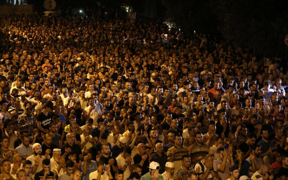 Palestinian men take part in evening prayers inside Jerusalem's Old City next to the Lion's Gate - Credit: Reuters