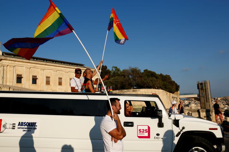 Participants wave rainbow flags from a Hummer Limousine during the Malta Pride Parade in Valletta