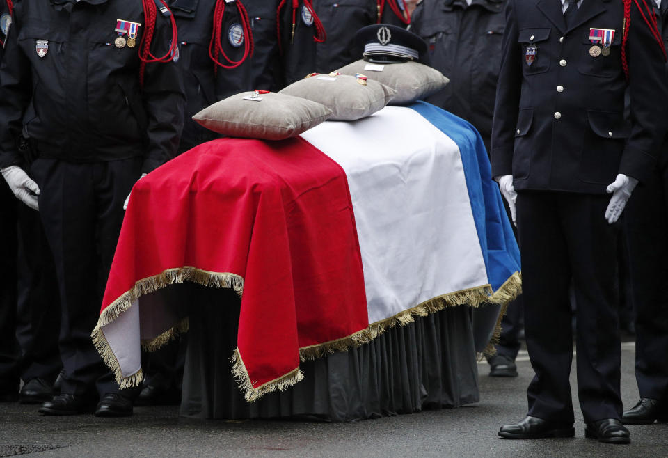 Medals are pictured on a coffin one of the four victims of last week's knife attack during a ceremony in the courtyard of the Paris police headquarters Tuesday, Oct. 8, 2019 in Paris. France's presidency says the four victims of last week's knife attack at the Paris police headquarters will be posthumously given France's highest award, the Legion of Honor. (AP Photo/Francois Mori)