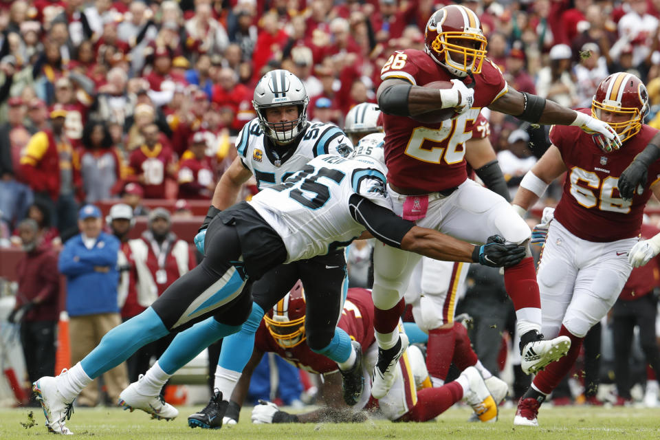 Washington Redskins running back Adrian Peterson (26) is stopped by Carolina Panthers safety Eric Reid (25) during the first half of an NFL football game, Sunday, Oct. 14, 2018, in Landover, Md. (AP Photo/Pablo Martinez Monsivais)