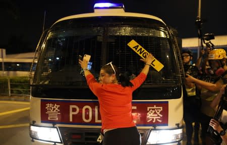 An anti-government demonstrator stands in fron of a police vehicle during a protest against the invocation of the emergency laws in Hong Kong