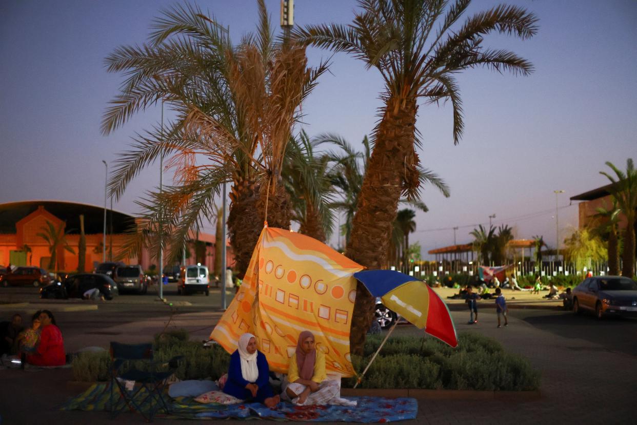 Marrakech residents seek shelter under a palm tree (REUTERS)