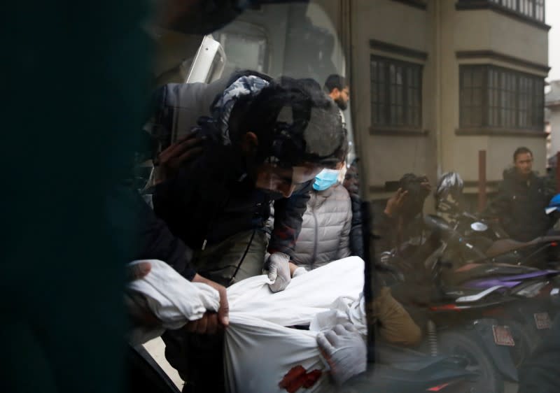 The body of a victim who is among the eight Indian tourists who died due to suspected suffocation is being carried inside an ambulance while being taken for postmortem in Kathmandu