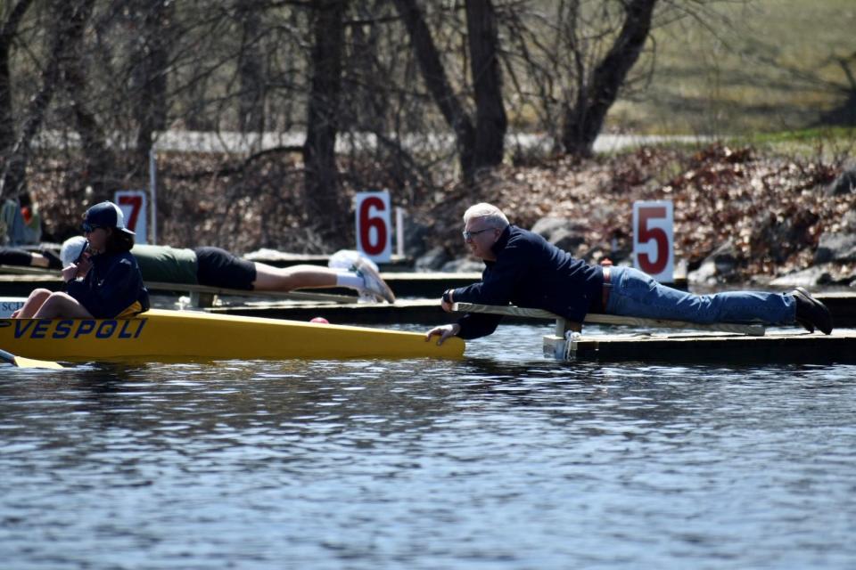 At the starting line, eight people sit on small docks in the water ready to "attach" the racing shells (left) to the stakeboats (right).