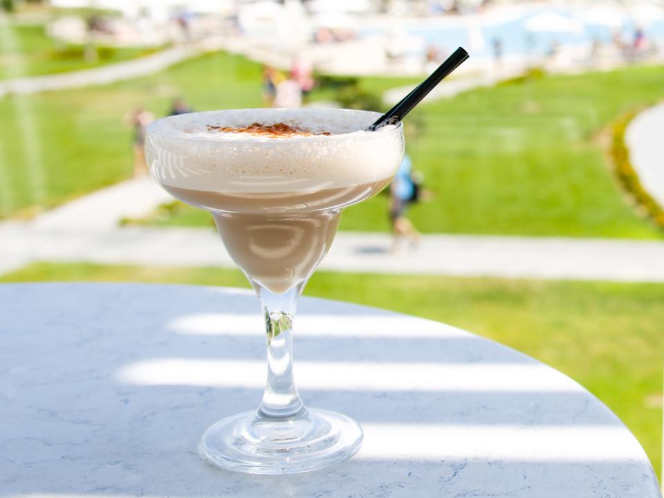 brandy alexander on a table outside overlooking a lawn and a pool
