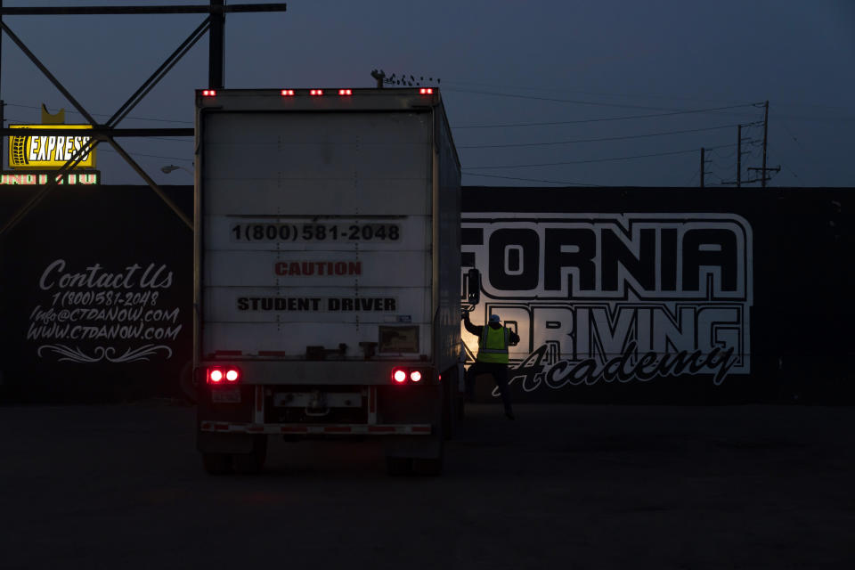 Evening class instructor Pavel Cruz gets off a practice truck after talking to his student at California Truck Driving Academy in Inglewood, Calif., Wednesday, Nov. 17, 2021. Business is booming at a truck-driving academy in suburban Los Angeles amid a nationwide shortage of long-haul drivers. The California Truck Driving Academy in Inglewood has seen annual enrollment grow by almost 20% since last year. (AP Photo/Jae C. Hong)