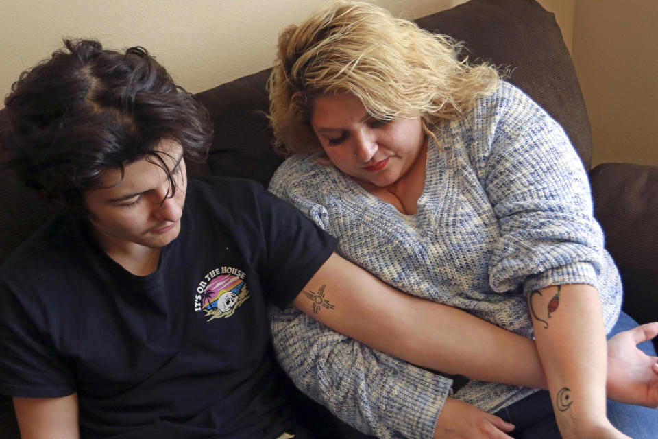 Javin Lujan Lopez, 17, a senior at Pojoaque High School, and his mother, Tracy Lujan, show tattoos that they got together, at their home, in Espanola, N.M., Feb, 22, 2021. Tracy Lujan was diagnosed with COVID-19 last fall. (AP Photo/Cedar Attanasio)