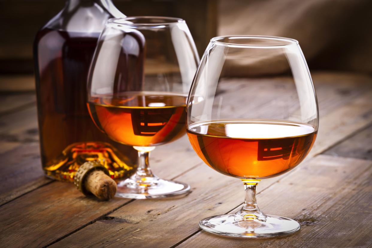 Front view of two cognac snifters and a open cognac bottle shot on rustic wood table. Low key DSRL studio photo taken with Canon EOS 5D Mk II and Canon EF 70-200mm f/2.8L IS II USM Telephoto Zoom Lens