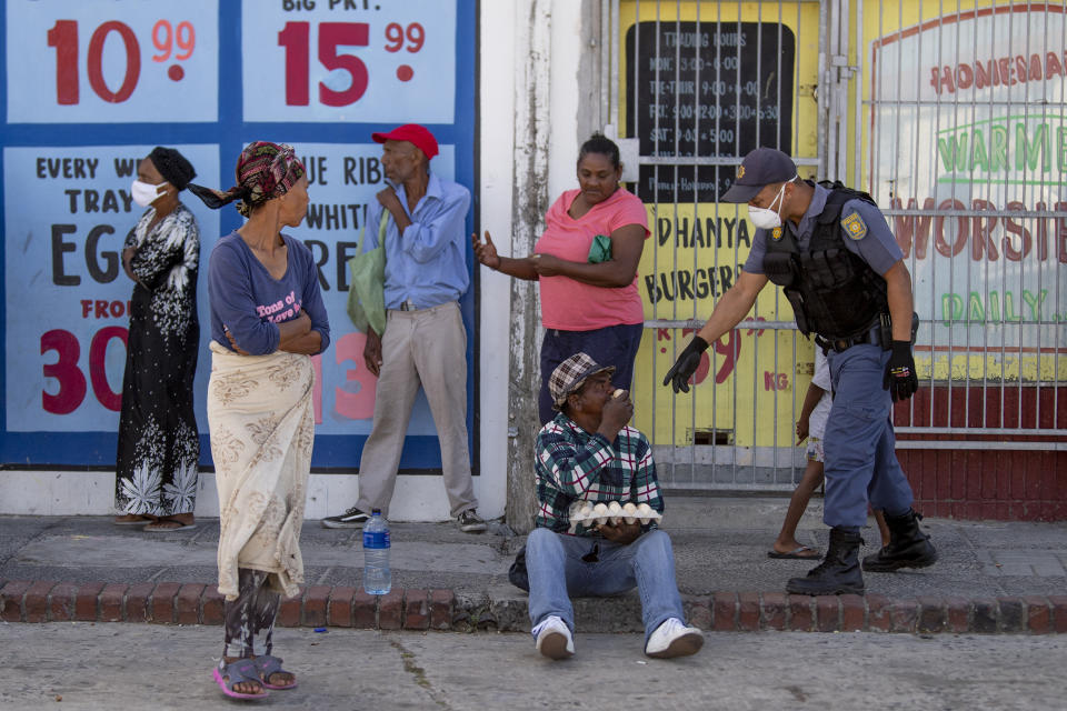 A policeman orders a loitering man to get home while patrolling in Mannenburg, Cape Town, South Africa, Saturday, March 28, 2020. South Africa went into a nationwide lockdown to restrict public movements for 21 days in an effort to control the spread of the COVID-19 coronavirus. (AP Photo)