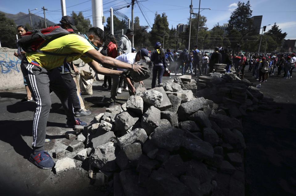 Volunteers dismantle a barricade in a major cleanup effort in the aftermath of violent protests against the government, in Quito, Ecuador, Monday, Oct. 14, 2019. Ecuador celebrated a deal President Lenín Moreno and indigenous leaders struck late Sunday to cancel a disputed austerity package and end nearly two weeks of protests that have paralyzed the economy and left seven dead. (AP Photo/Fernando Vergara)