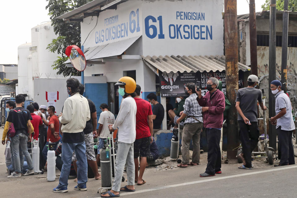 People wait for their turn to refill their oxygen tanks at a recharging station in Jakarta, Indonesia, Friday, July 9, 2021. Just two months ago, Indonesia was coming to a gasping India's aid with thousands tanks of oxygen. Now, the Southeast Asia country is running out of oxygen as it endures a devastating wave of coronavirus cases and the government is seeking emergency supplies from other countries, including Singapore and China. (AP Photo/Tatan Syuflana)