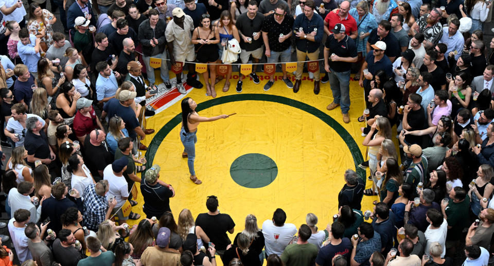 A woman plays two-up as thousands of people watch her.