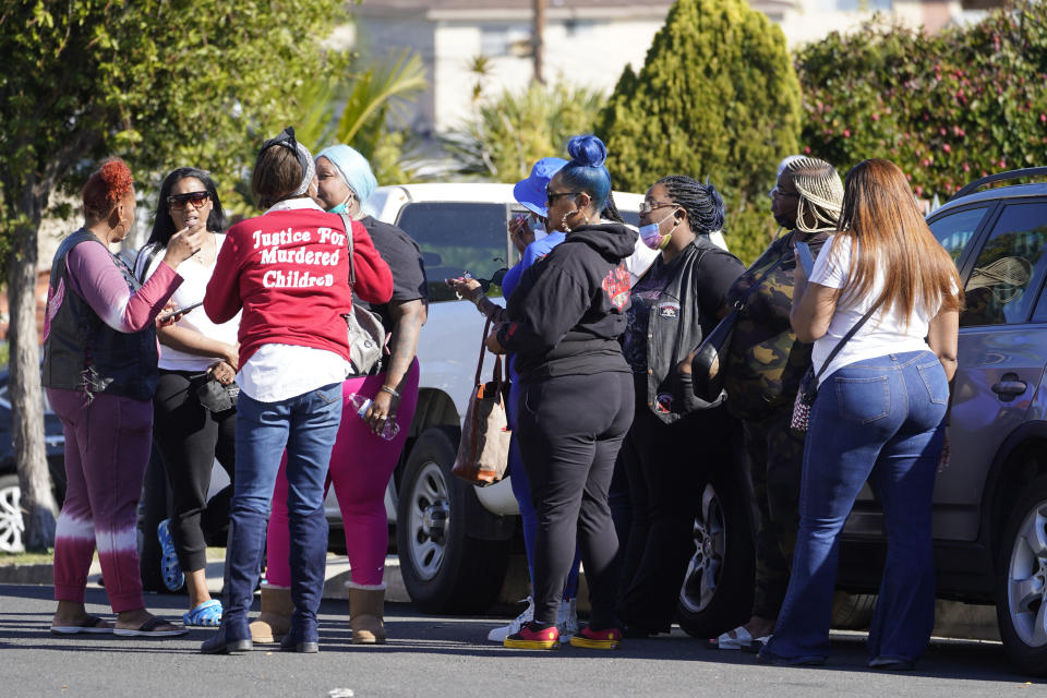 People gather on Park Avenue near the scene of a shooting in Inglewood, Calif., on Sunday, Jan. 23, 2022. Authorities said several were killed when multiple shooters opened fire at a house party near Los Angeles early Sunday. (AP Photo/Damian Dovarganes)