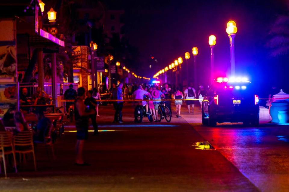 Pedestrians and bicyclist move around a Hollywood Police Car as it sits parked on the 1214 block of North Broadwalk near Nick’s Bar and Grill after police responded to reports of multiple people shot during Memorial Day weekend at Hollywood, Florida, on Monday, May 29, 2023.