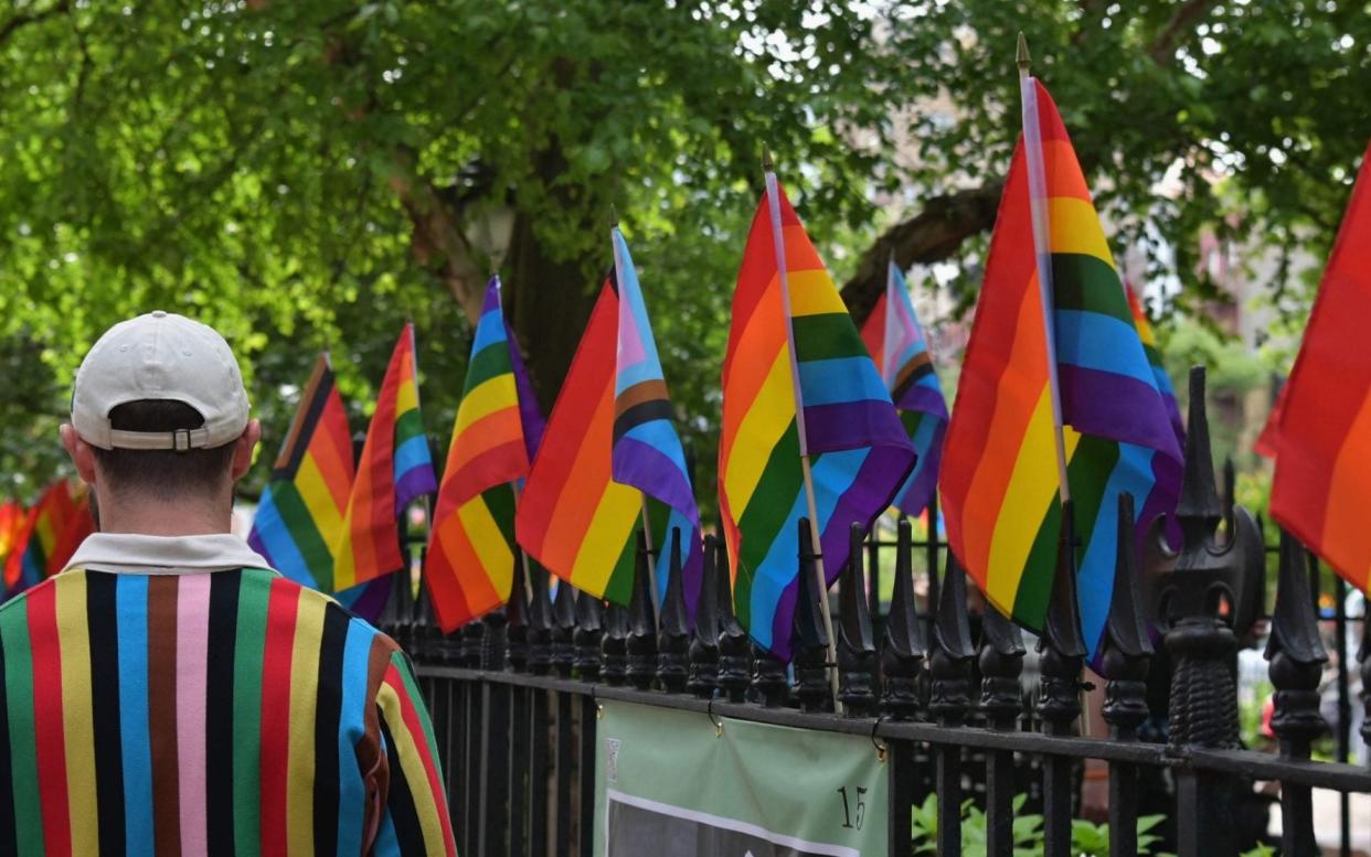  A person wearing a sweater with 'Progress Pride Flag' colors, including rainbow and black and brown stripes for communities of color, walks past rainbow flags at the Stonewall National Monument, the first US national monument dedicated to LGBTQ history and rights, marking the birthplace of the modern lesbian, gay, bisexual, transgender, and queer civil rights movement, on June 1, 2020 in New York City. (Photo by Angela Weiss / AFP) (Photo by ANGELA WEISS/AFP via Getty Images) - Angela Weiss/AFP via Getty Images